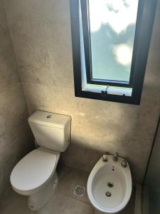 a bathroom with a toilet and a sink and a window at Departamento y aire libre in General Pico