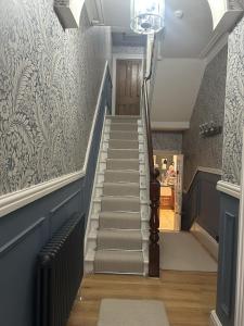 a hallway with stairs with blue and white wallpaper at The Welford in Harrogate