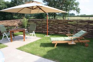 a patio with an umbrella and a table and chairs at Ferienhaus Sweet-Escape in Löningen