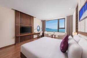a hotel room with a bed and a tv at Rosamia Da Nang Hotel - My Khe Beachfront Luxury in Danang
