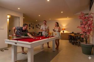 a group of people standing around a pool table at Villa de lujo con jacuzzi, cine, billar y futbolín in Murcia