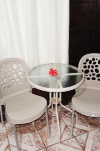 a glass table with two chairs and a red bow on it at Casa da Silvana in Fernando de Noronha