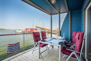 a deck with a table and chairs on a boat at Hausboot Sunshine Heiligenhafen in Viehhof