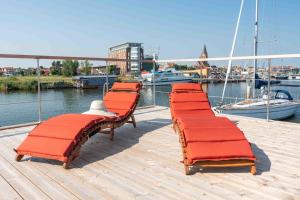 a row of red benches on a dock near the water at Hausboot Sunshine Heiligenhafen in Viehhof +6 photos