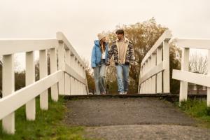 a man and a woman walking across a bridge at MarinaPark Beach Resort Soal | Beachfront villas in Workum +14 photos
