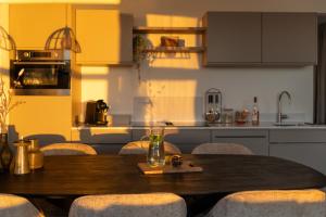 a kitchen with a wooden table with chairs and a kitchen with yellow cabinets at MarinaPark Beach Resort Soal | Beachfront villas in Workum