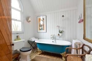 ein Badezimmer mit einer blauen Badewanne und einer Toilette in der Unterkunft The Tabernacle, Design-led Converted Chapel with Hot Tub, Highland Perthshire in Aberfeldy