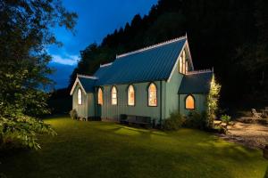 Eine grüne Kirche mit eingeschalteter Beleuchtung in einem Hof in der Unterkunft The Tabernacle, Design-led Converted Chapel with Hot Tub, Highland Perthshire in Aberfeldy + 44 Fotos
