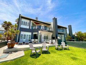 a house with chairs and a table in the yard at Pebble Beach Seafront Condo in Swakopmund