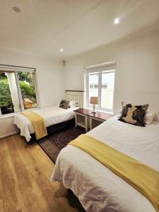 a bedroom with two beds and a desk and two windows at Art House in Stellenbosch