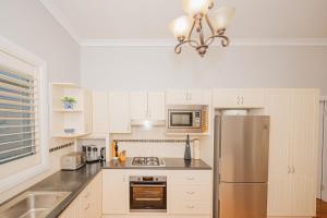 a kitchen with white cabinets and a stainless steel refrigerator at Cozy Cottage with Full Kitchen, Backyard & Patio in Tamworth