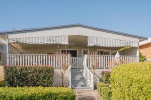 a white house with a white fence and bushes at Cozy Cottage with Full Kitchen, Backyard & Patio in Tamworth