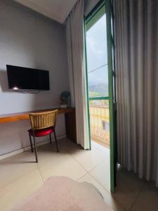 a room with a television and a chair and a window at Pousada Solar dos Guarás in Catas Altas