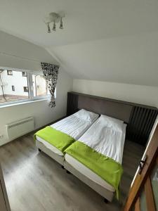 a bedroom with a bed with green sheets and a window at Zielony Cypel in Lubniewice