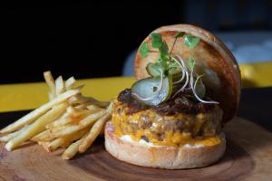 a sandwich and french fries on a wooden plate at Audace Motel in Porto Alegre