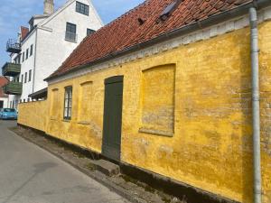a yellow brick building with a door on a street at City gæstehus kerteminde in Kerteminde