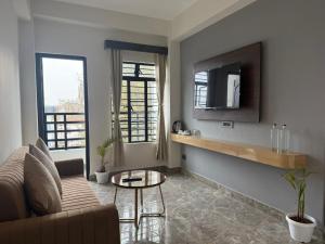 a living room with a couch and a tv on the wall at The Notting Hills Inn in Shillong