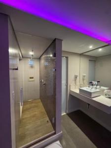 a bathroom with a shower and a sink with a purple lighting at Flow Motel (Adult Only) in Valinhos +17 photos
