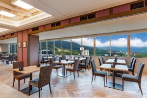 a restaurant with tables and chairs and large windows at KAMENOI HOTEL Kusatsu Resort in Kusatsu