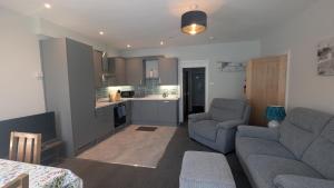 a living room with two couches and a kitchen at Buile Hill Holiday Flats in Llandudno