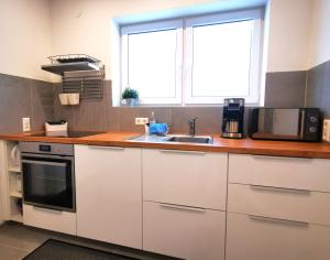 a kitchen with white cabinets and a sink and a window at Gemütliches Souterrain in Langenargen in Langenargen