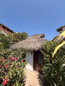 a small hut with a thatched roof and flowers at CASA AUM in Brisas de Zicatela +8 photos