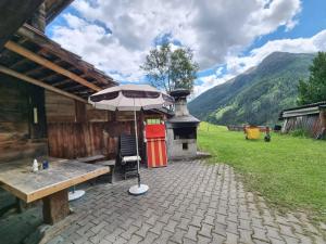 a picnic table with an umbrella next to a building at Ferienhaus im Bergidyll in Sankt Jakob in Defereggen
