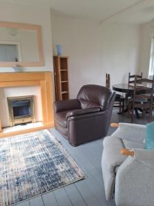 a living room with a leather couch and a fireplace at Hazel's House in Keighley