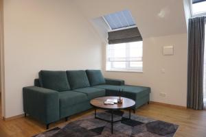 a living room with a green couch and a table at Modern New-Build Apt, managed by RentiFor in Klaipėda