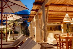 a patio with chairs and an umbrella and a table at Masseria Messapia Wine Resort & Spa Salento in Mesagne
