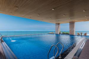 a swimming pool with a view of the ocean at Rosamia Da Nang Hotel - My Khe Beachfront Luxury in Danang