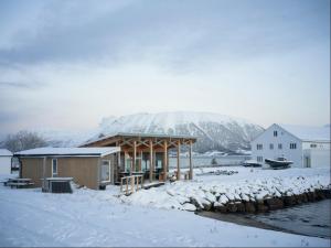 a house in the snow with mountains in the background at Arctic Ocean Lodge in Skjolde
