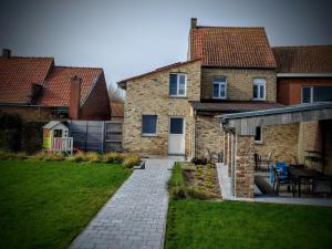 a brick house with a patio and a table at Up de platse in Lo-Reninge