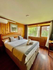a bedroom with a large bed with wooden walls at Hotel Costanera Pucón in Pucón