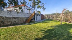 a house with a stone wall and a grass yard at Quinta da Toqueira in Canedo