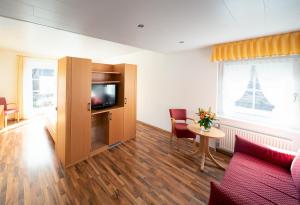 a living room with a couch and a tv and a table at Hotel zum Moselstrand in Briedern