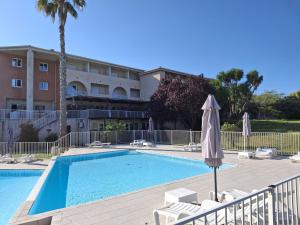 a swimming pool with an umbrella next to a hotel at SAINT-FLORENT Studio PISCINE FLO300-146 in Saint-Florent