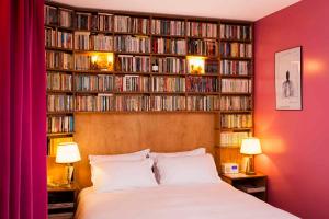 a bedroom with a bed and a book shelf filled with books at Hôtel Grand Amour in Paris