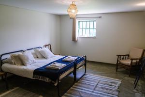 a bedroom with a bed and a chair and a window at Casa do Outeiro in Vila Meã