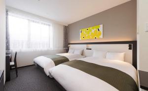 a hotel room with two beds and a window at Osaka Airterminal Hotel in Toyonaka