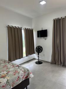 a bedroom with a bed and a television and curtains at Chalé portal da serra in Serra do Cipo