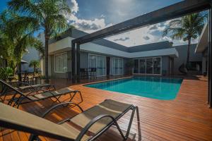 a swimming pool on a wooden deck with chairs at Hotel Opuka in Sorriso