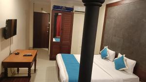 a hotel room with a bed and a table and a television at WoodLand Suites in Cochin
