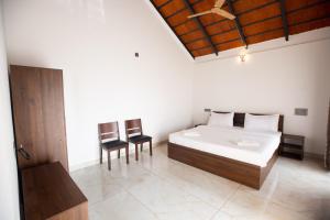 ein Schlafzimmer mit einem Bett, zwei Stühlen und einer Decke in der Unterkunft The Nest Bettathur, Coorg in Madikeri + 82 Fotos