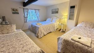 a bedroom with three beds and a window at Bickleigh Castle - A Majestic Devon Estate for Exclusive Gatherings in Winkleigh