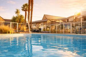 a swimming pool in front of a house with palm trees at Les Treize Assiettes - Baie du Mont-Saint-Michel in Le Val-Saint-Père