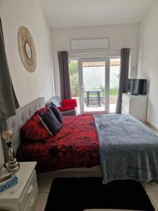 ein Schlafzimmer mit einem Bett mit roter Bettdecke und einem Fenster in der Unterkunft Cassis la gare in Cassis
