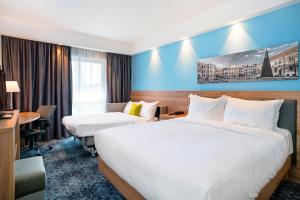 a hotel room with two beds and a desk at Hampton By Hilton Lublin in Lublin +19 photos