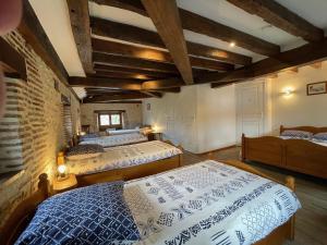 a bedroom with two beds and a brick wall at Chambres d’hôtes Le relais de Mantelot in Châtillon-sur-Loire