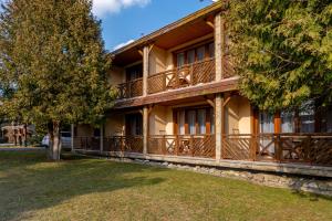 a house with wooden balconies and a tree at Hotel Ranč u Edyho in Námestovo